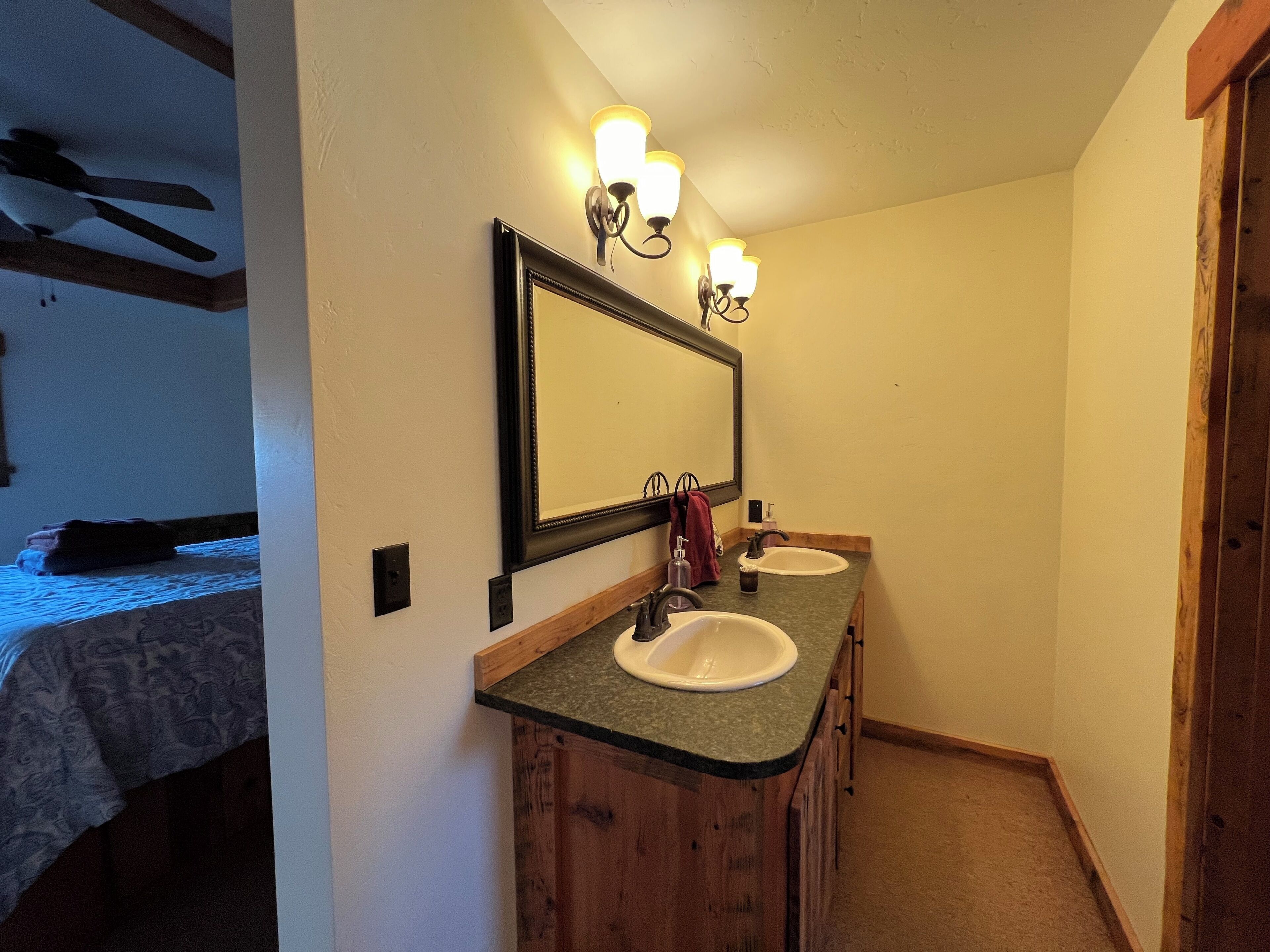 A bathroom with two sinks, a mirror, and a ceiling fan.