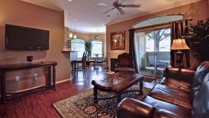 A living room with a leather sofa, a coffee table, a TV, and a ceiling fan. - Amazing Casita with Upgrades Galore! (Scottsdale)