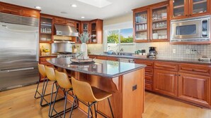 Una cocina moderna con armarios de madera, electrodomésticos de acero inoxidable y una isla central con taburetes de bar.
