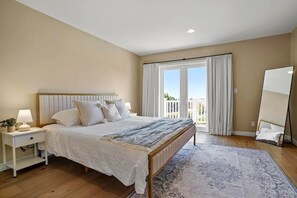 Een slaapkamer met een bed, nachtkastje, lamp en een grote spiegel.