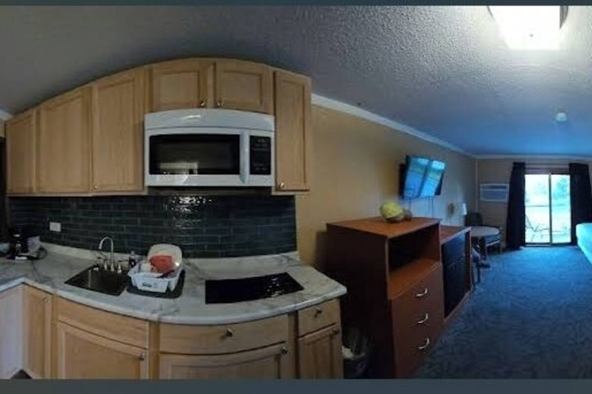 A compact RV-style room with a kitchenette, a bed, and a bathroom.