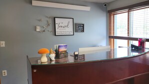A reception desk with framed quotes, a small statue, and a glass-top counter. - Hampton Motel (Hampton)