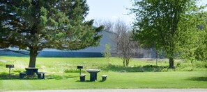 A grassy area with picnic tables and a building in the background.