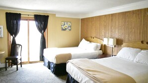 A hotel room with two beds, a chair, a desk, and a window with curtains. - Hampton Motel (Hampton)