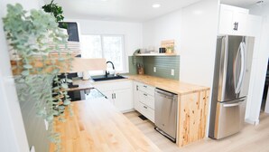 A modern kitchen with wooden countertops, stainless steel appliances, and a green backsplash. - Family-Friendly, Modern Home with Extra Large Hot Tub with EV Charger (Sisters)