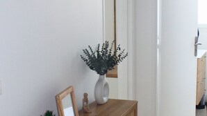 Ett konsolbord i trä med en vas och en inramad tavla mot en vit vägg.