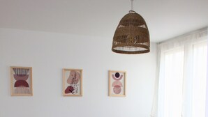 Ett sovrum med en säng, sängbord, en hängande lampa och konst på väggen.