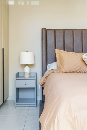 A hotel room with a bed, a nightstand with a lamp, and a window with curtains.