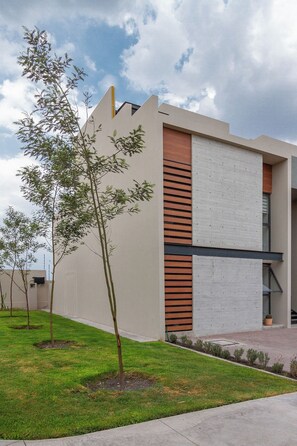 A modern building with a flat roof, a concrete facade, and a section with horizontal wooden slats.