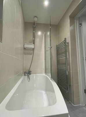 A modern bathroom with a freestanding bathtub, a glass shower enclosure, and a towel rack.