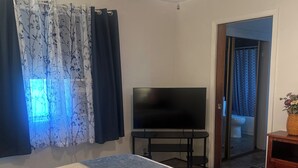 A bedroom with a bed, a TV, a ceiling fan, and a bathroom visible through an open door. - Cozy 3BR Home in Chester Near Lake Almanor and Mt Lassen (Chester)