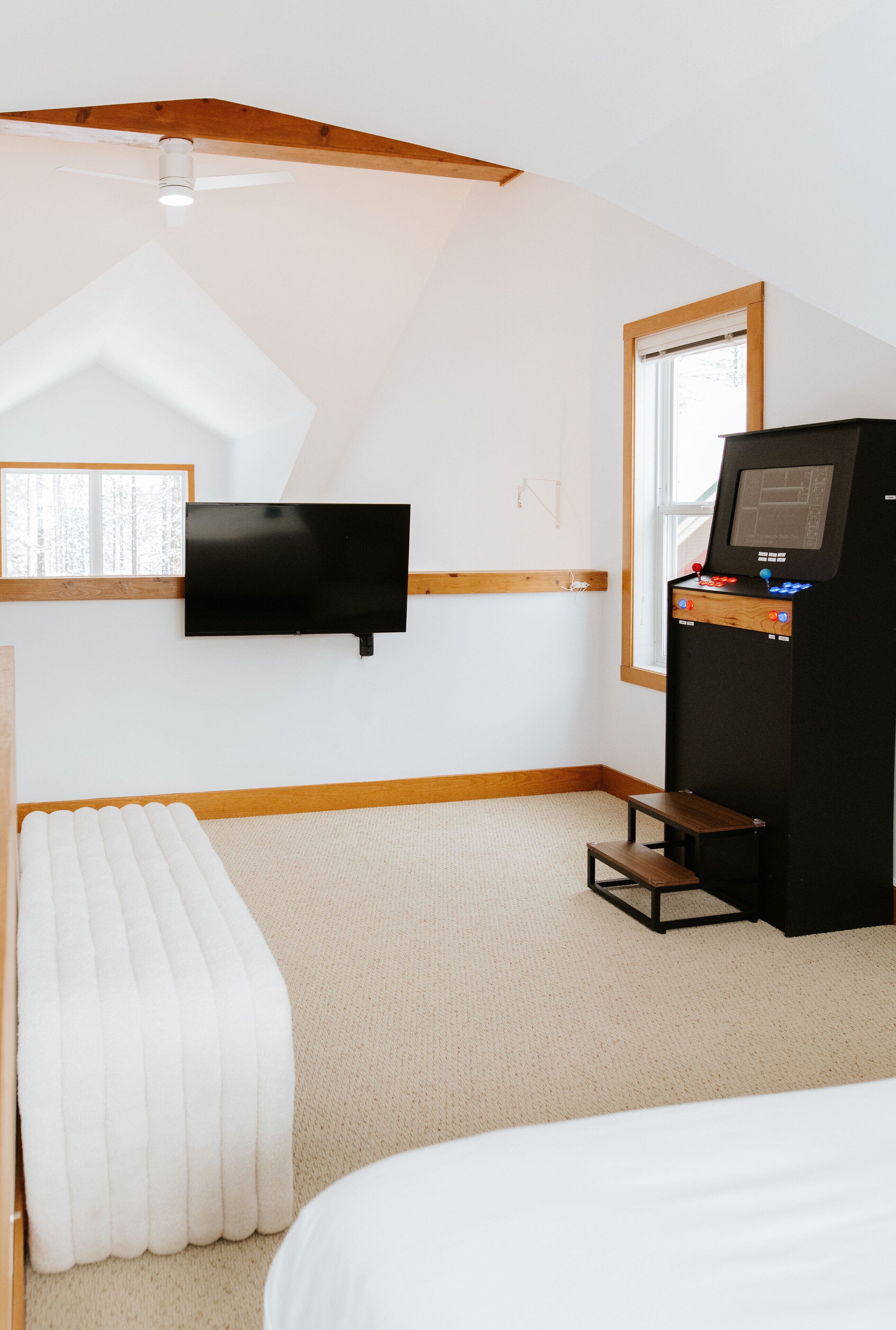 A hotel room with a bed, a television mounted on the wall, a small table, and a ceiling fan.
