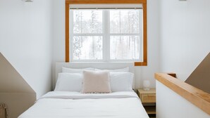 Ein Schlafzimmer mit einem Bett, einem Nachttisch, einem Fenster und einem Holzkopfende.