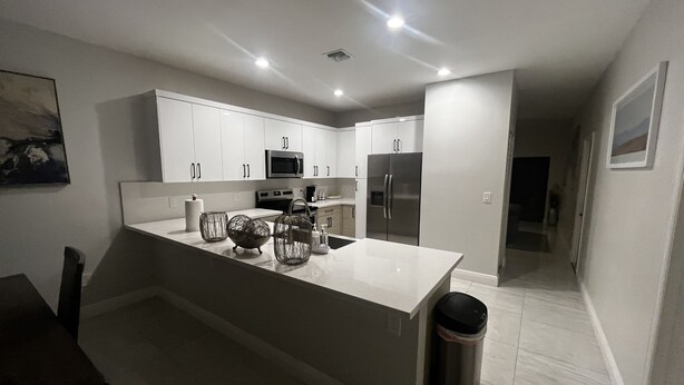 A modern kitchen with white cabinetry, stainless steel appliances, and a central island with decorative items.