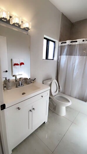 Un baño moderno con tocador blanco, inodoro y cortina de ducha.
