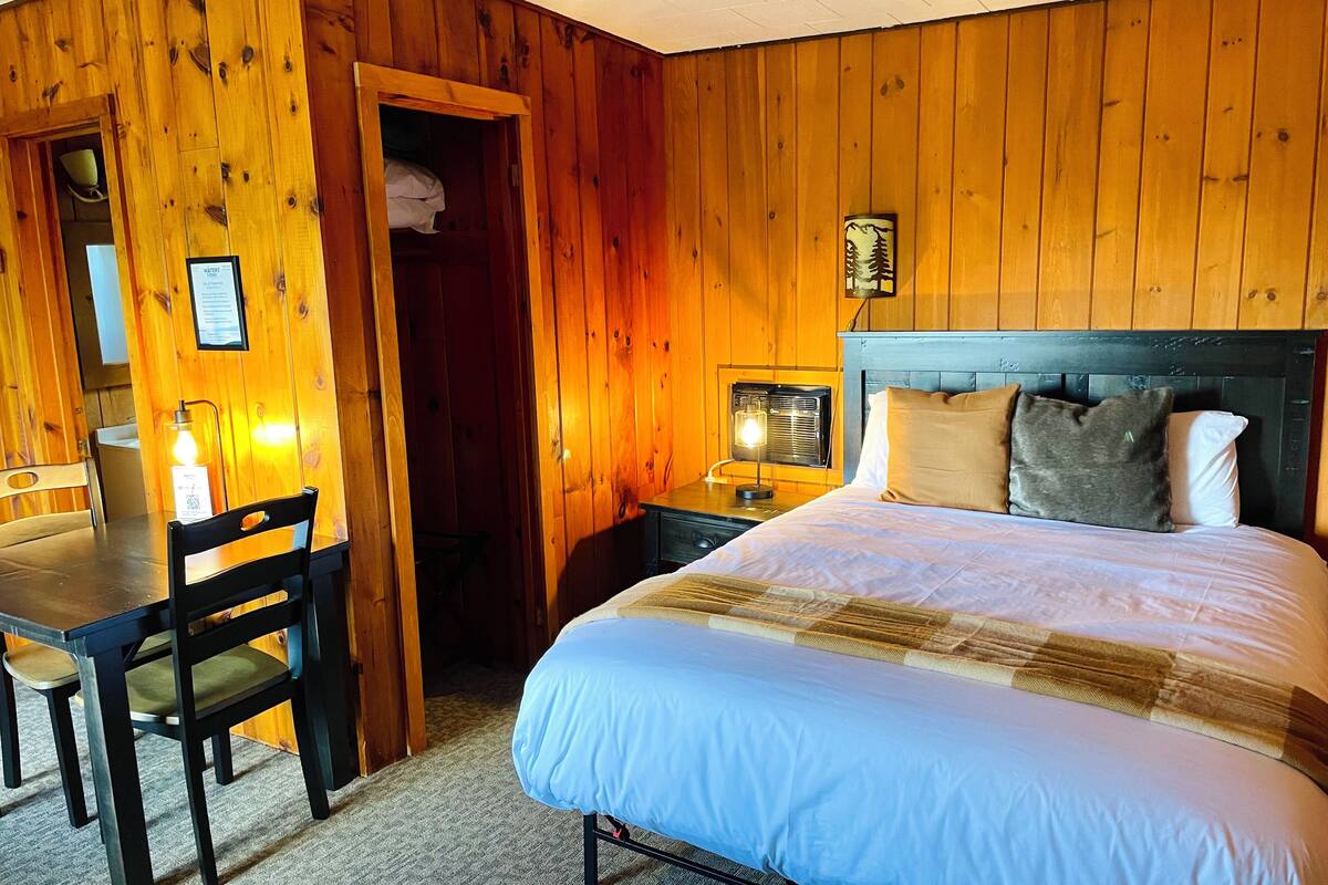 A wooden room with a bed, a desk, and a chair.