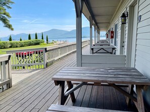 A wooden deck with a table and benches, overlooking a body of water and mountains.
