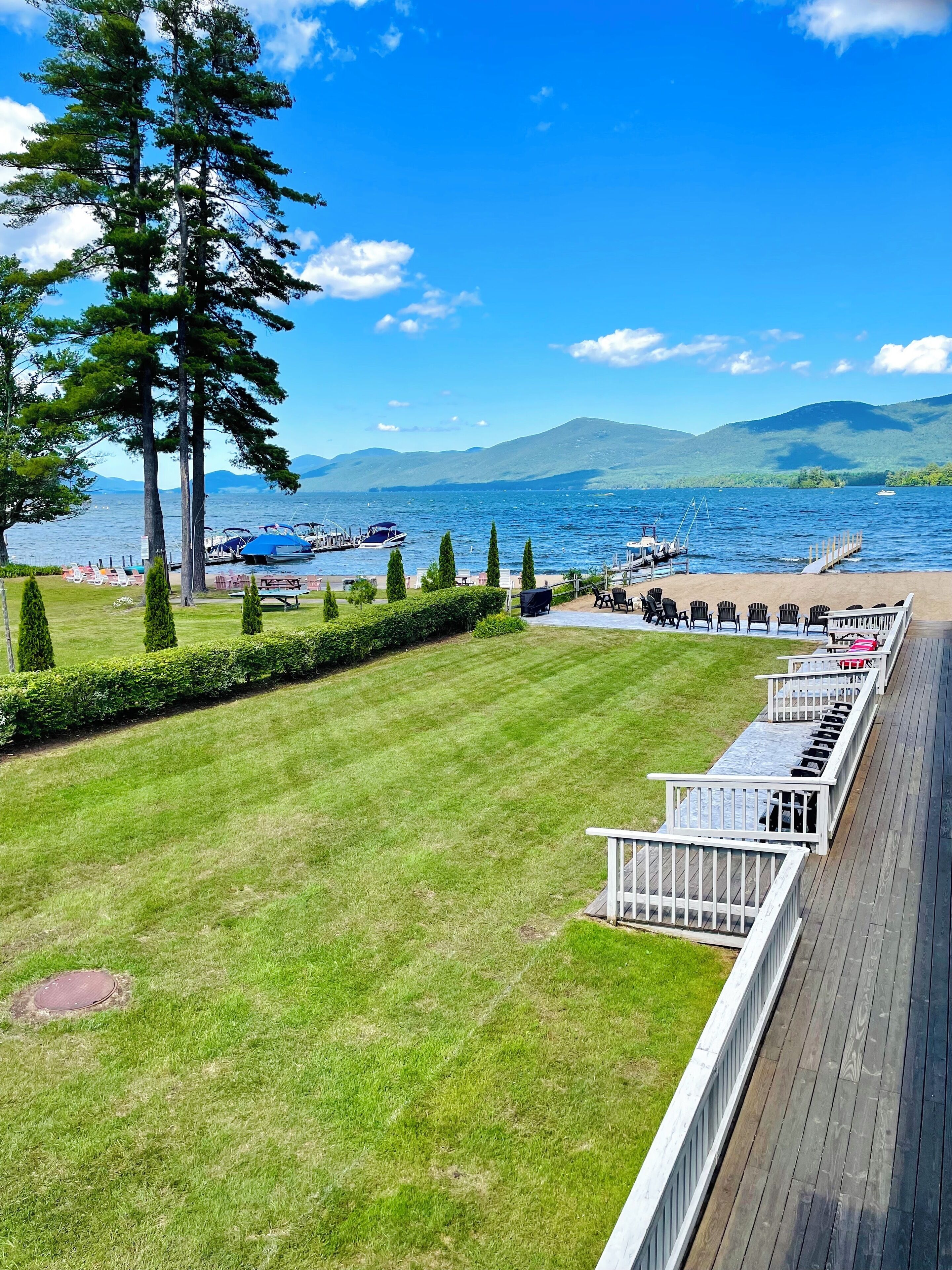 Eine Terrasse mit Sitzgelegenheit mit Blick auf einen See, umgeben von viel Grün und Bergen.