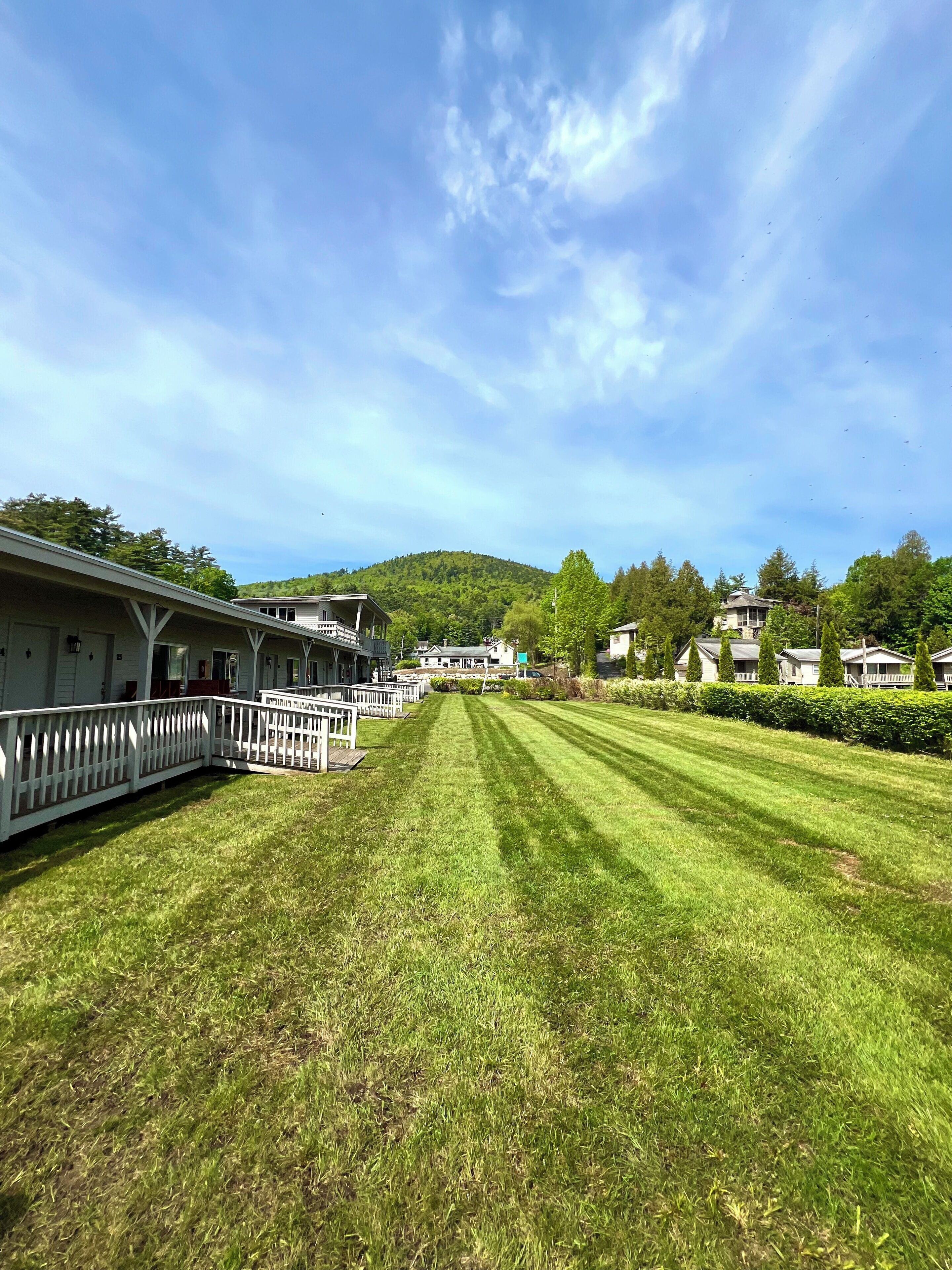 A well-maintained grassy lawn with a white fence and a building with a porch.