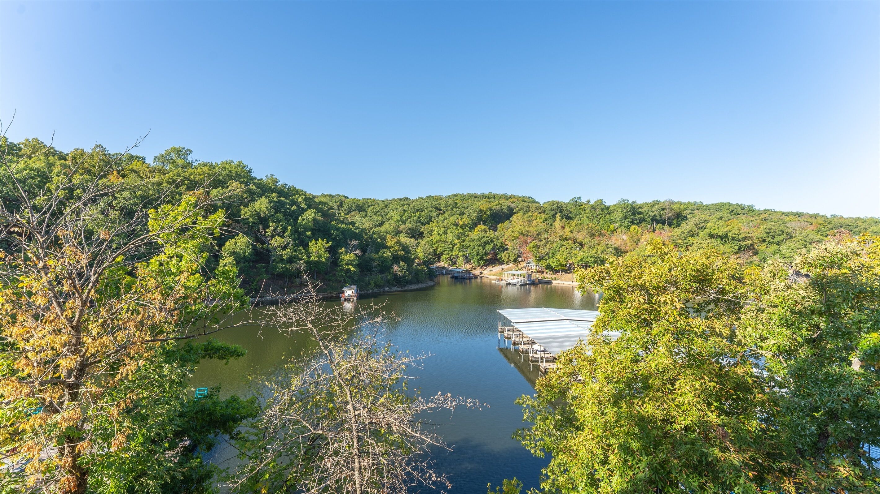 A riverside view with a dock and a house on the opposite bank.