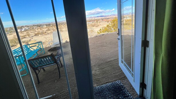 Una habitación con un amplio ventanal que da a un patio exterior con una banca y una mesa.