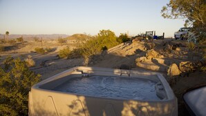 Un jacuzzi en un entorno desértico con paisaje rocoso y vegetación escasa.