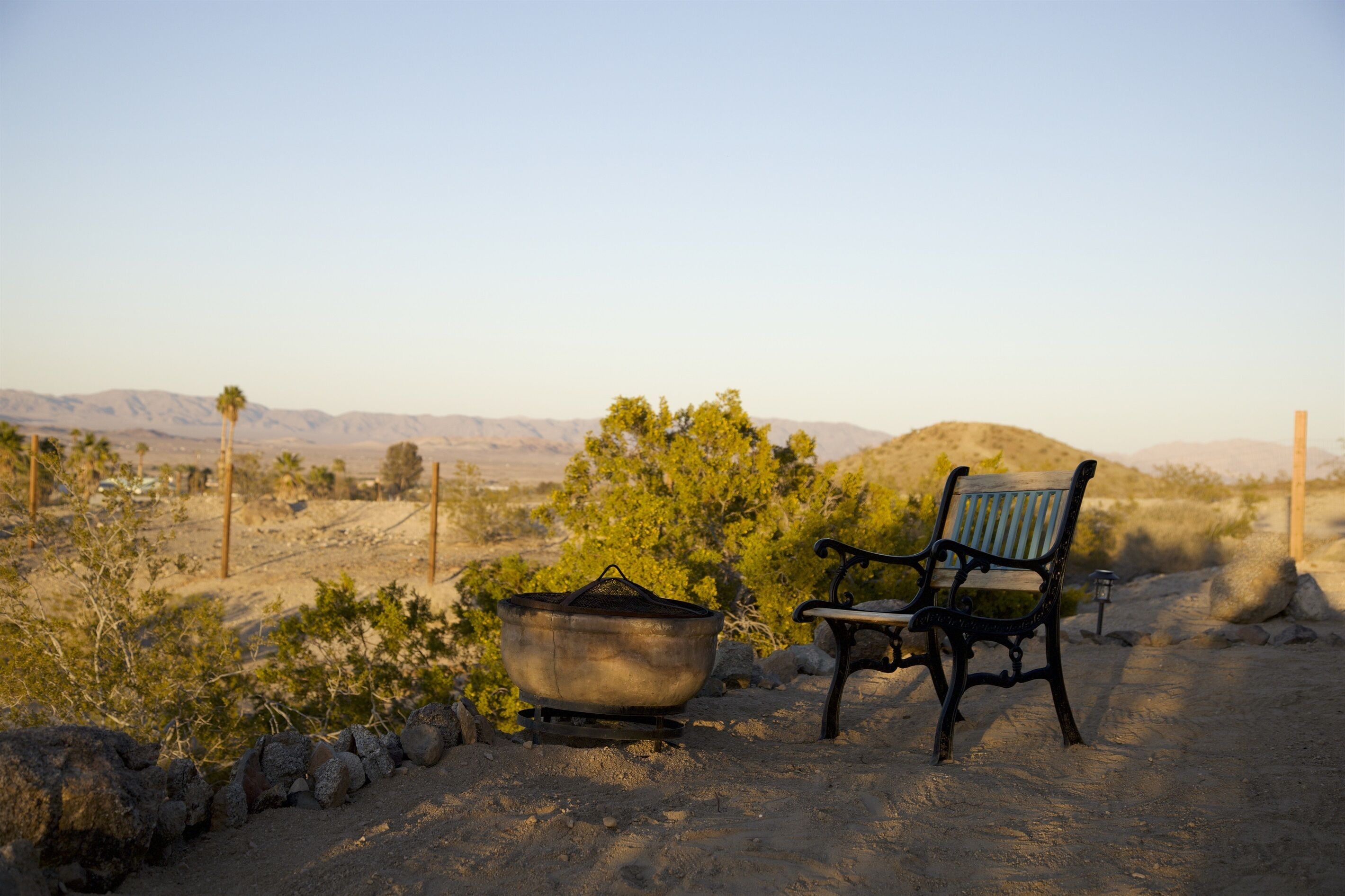 A desert landscape with a rustic bench and a large pot, suggesting a campsite or outdoor area.