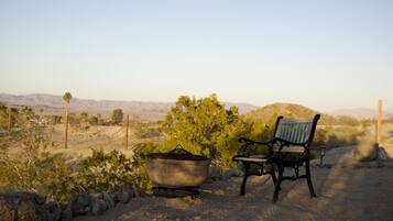 A desert landscape with a rustic bench and a large pot, suggesting a campsite or outdoor area.
