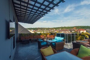 A rooftop terrace with outdoor seating and a view of a residential area. - BEDEX HOTEL AND SUITE (Abuja)