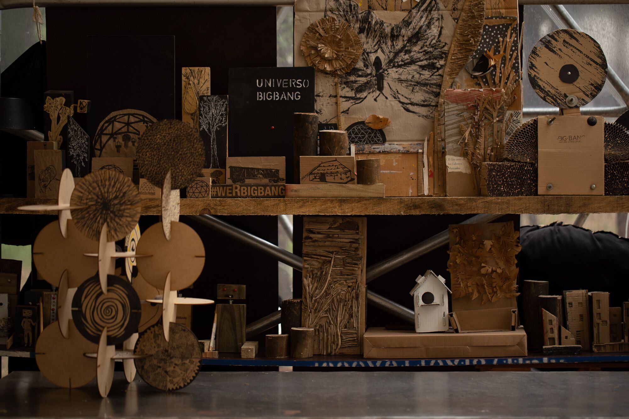A display of various wooden sculptures and models, including a large butterfly and a house model, on a wooden shelf.
