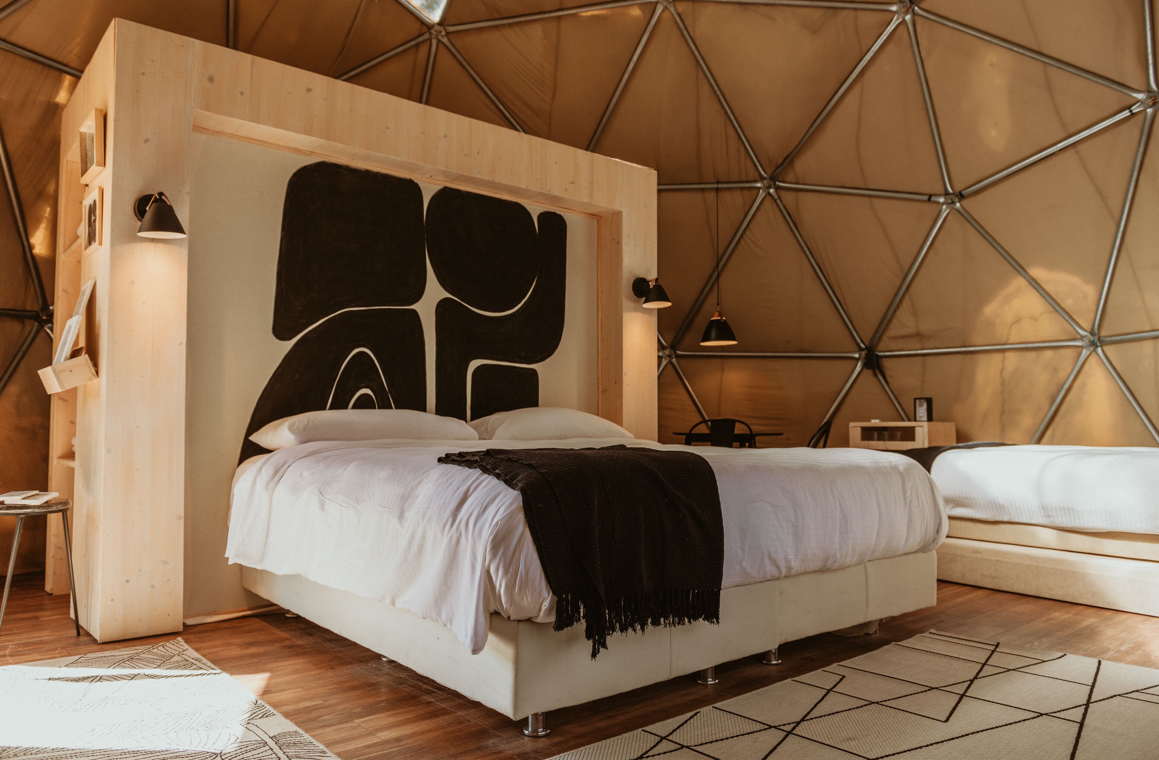 A modern, geometric-themed bedroom with a large bed, bedside tables, and a unique geometric wall design.