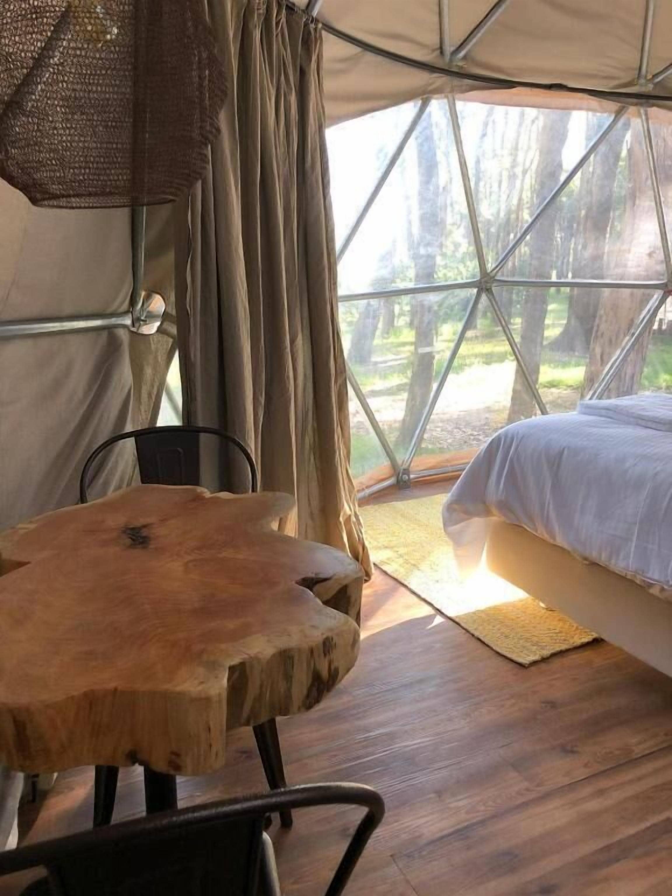 A tent with a bed, a table, and a chair inside.