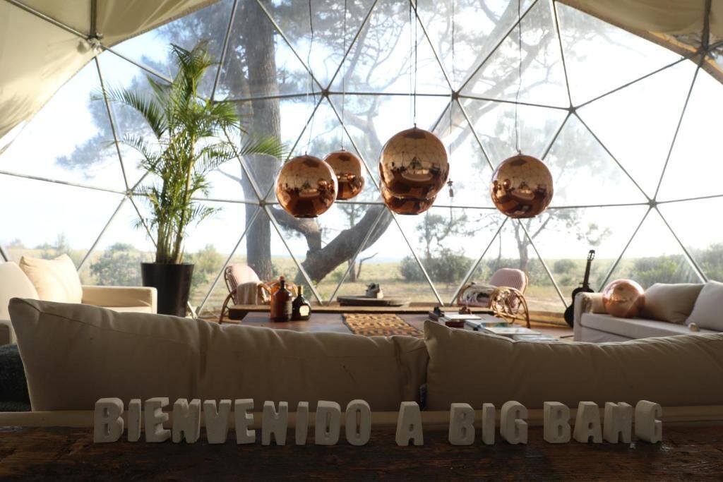 A spacious, well-lit room with a large, geometric window structure, a comfortable sofa, and a hammock.