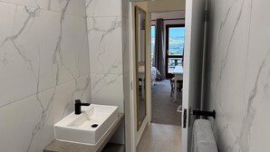 A modern bathroom with a marble backsplash, a white sink, and a towel rack. - Castleton 19B Family friendly  apartment, in a secure resort, in Plettenberg Bay (Plettenberg Bay)
