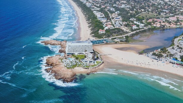 An aerial view of a coastal hotel with a beachfront, a large building with multiple floors, and a sandy beach area. - Castleton 19B Family friendly  apartment, in a secure resort, in Plettenberg Bay (Plettenberg Bay)