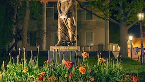 A statue of Mary Wells Morris in a garden with tulips and trees.