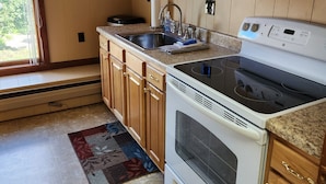 A kitchen with wooden cabinets, a microwave, a stove, and a sink.