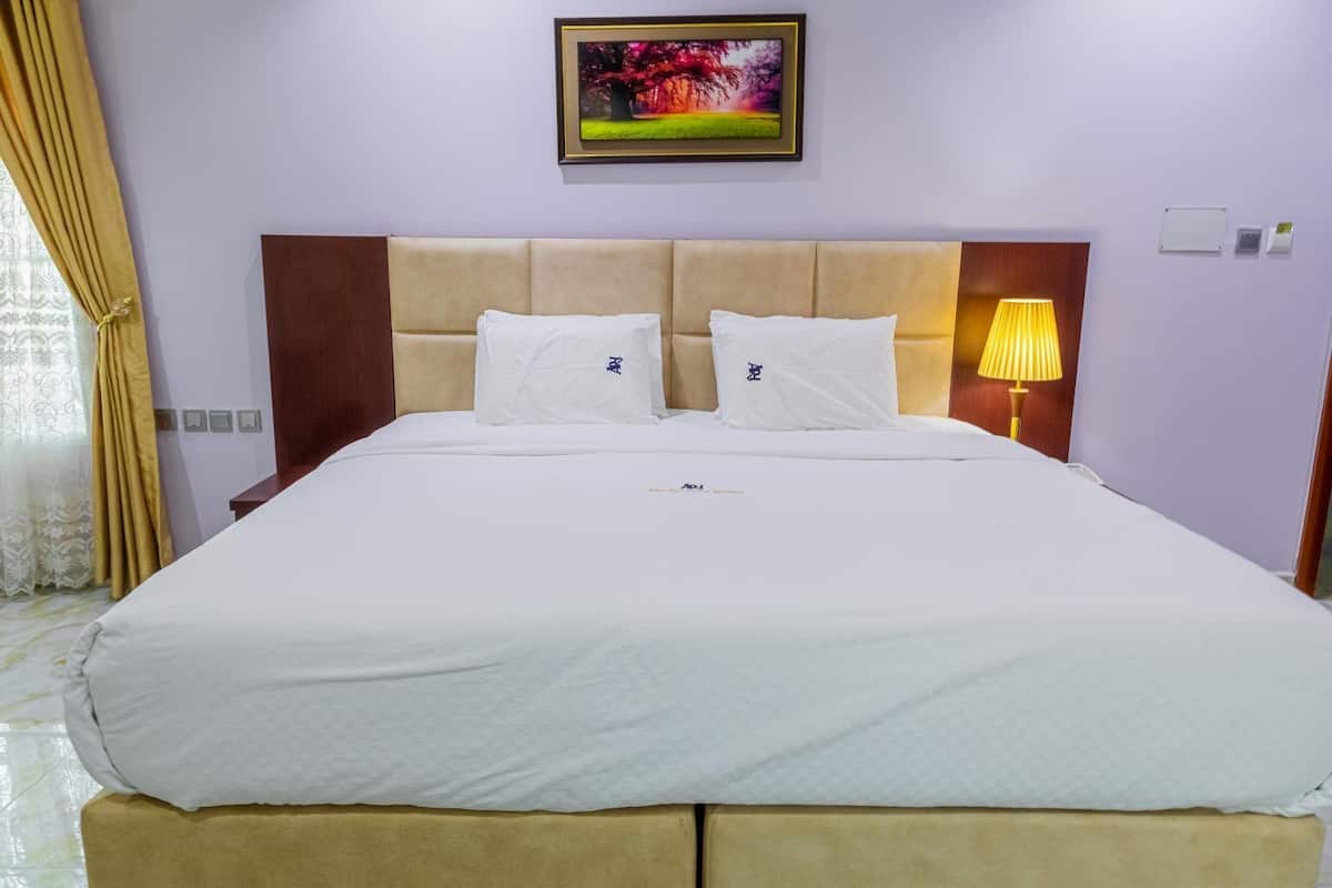 A double bed with two pillows, a headboard, a bedside lamp, and a framed picture on the wall.