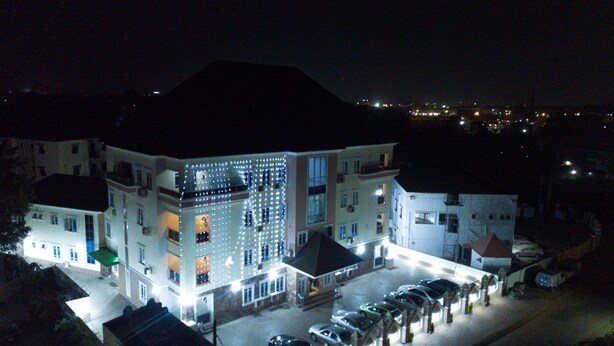 A multi-story hotel with a parking lot, illuminated by exterior lights. - Alheri Royal Apartment (Abuja)