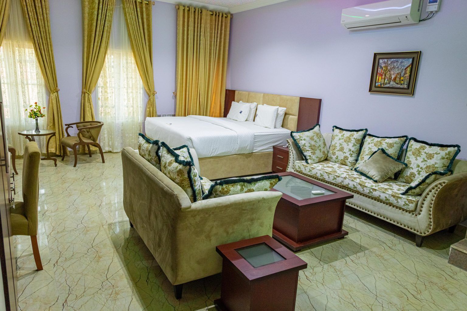 A hotel room with a bed, two sofas, a small table, and a chair.