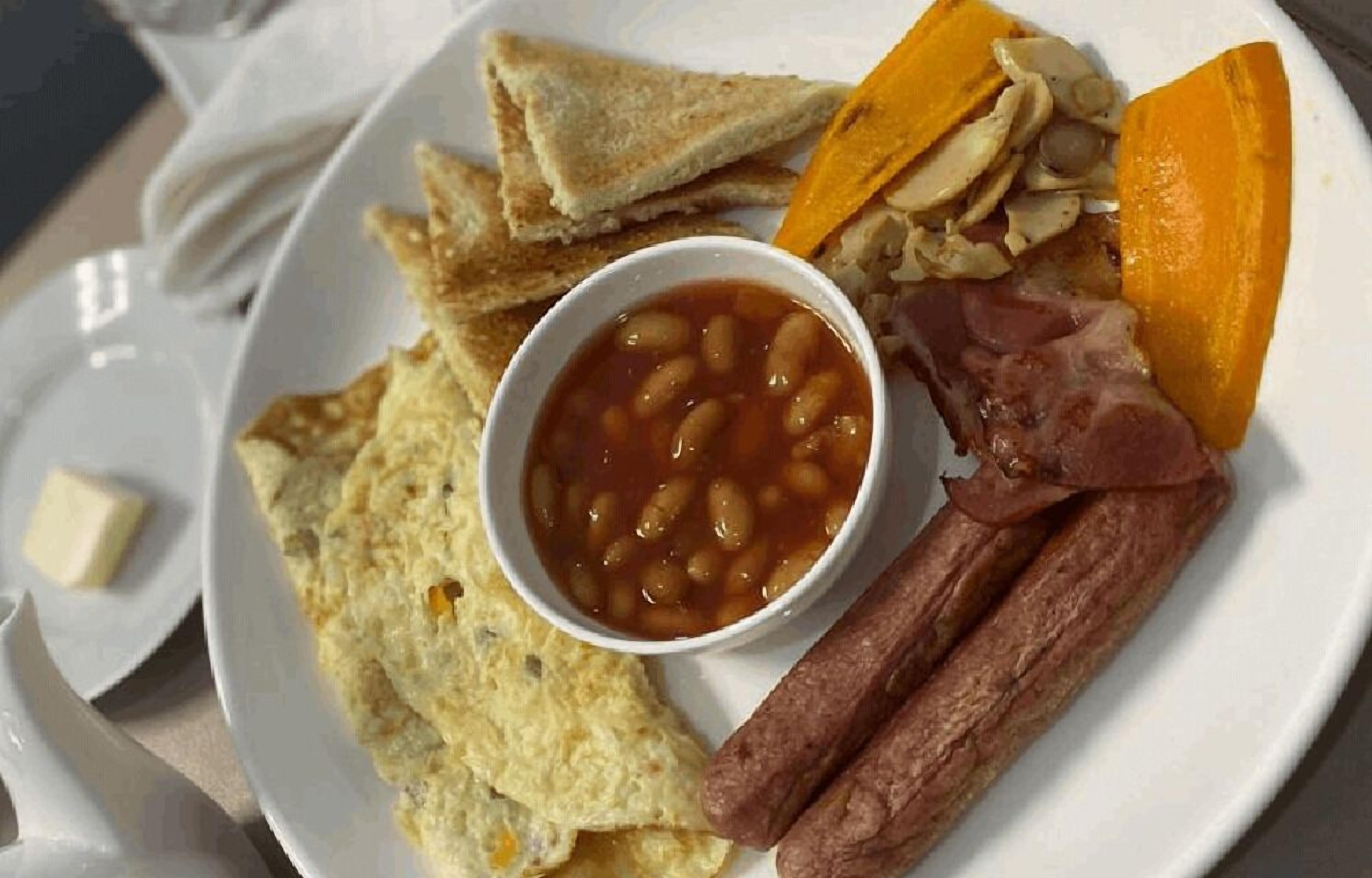 Un plato con tostadas, frijoles, salchichas y una rebanada de calabaza.