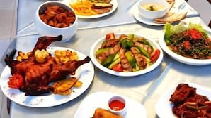 A table set with various dishes including fried chicken, spring rolls, and other meals. - Alheri Royal Apartment (Abuja)