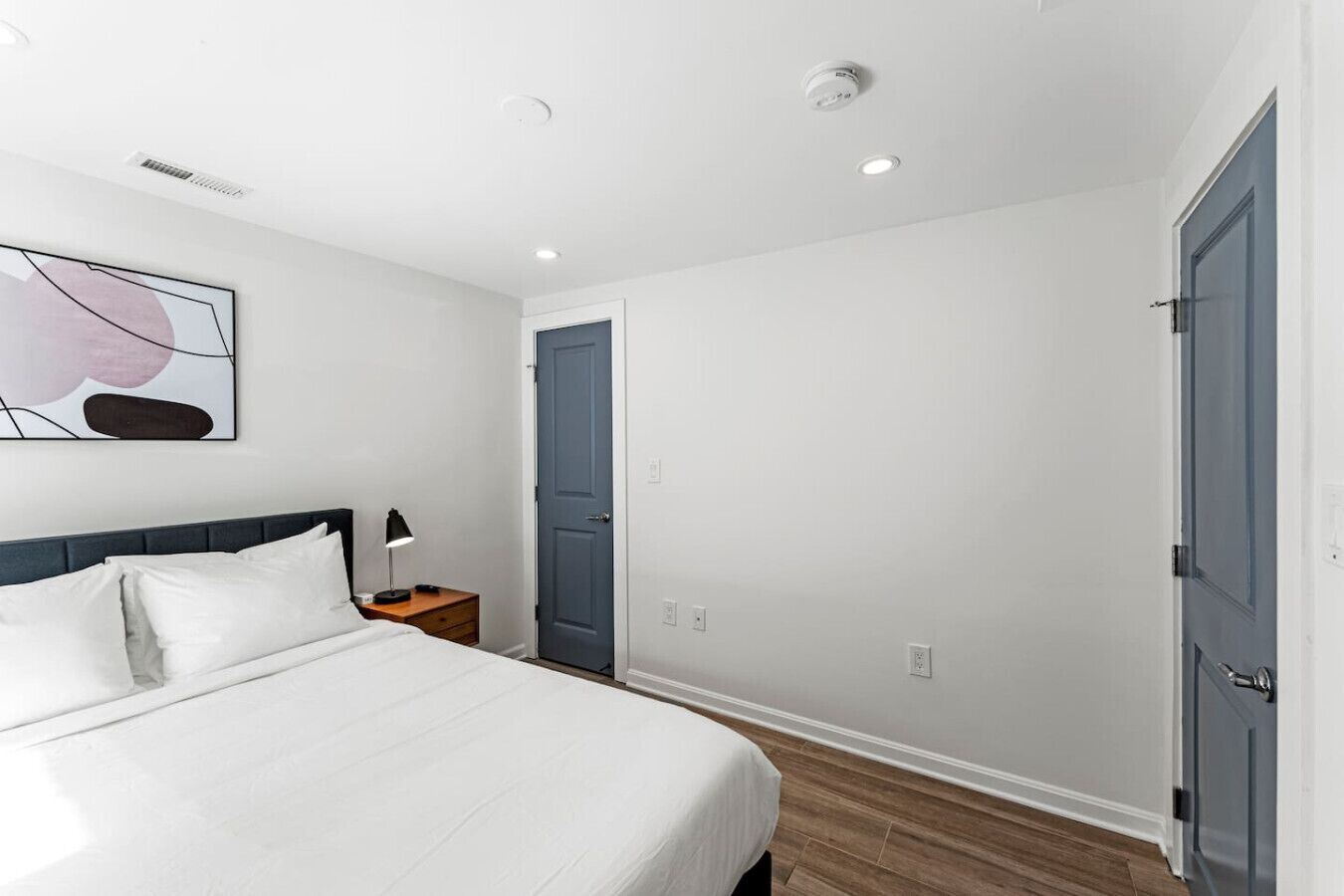 A modern bedroom with a bed, bedside table, and a door.