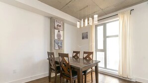 Un coin repas avec une table et des chaises en bois, un luminaire suspendu et une fenêtre avec des rideaux.