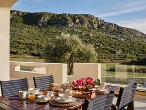 Una mesa lista para el desayuno, con una vista panorámica de montañas al fondo.