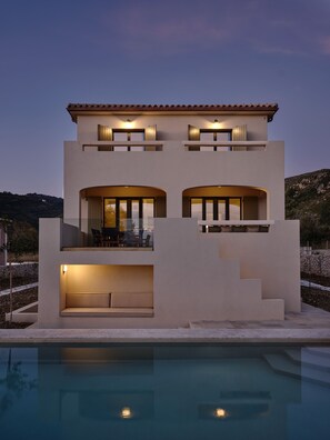 Una casa moderna de dos pisos con una piscina delantera.