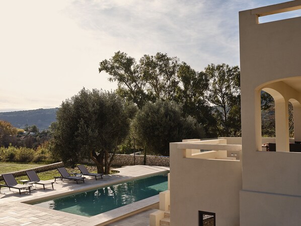 Zona de piscina con sillones de descanso y vistas del paisaje circundante.