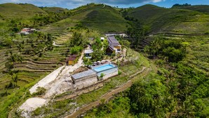 A hillside property with terraced fields, a swimming pool, and several buildings. - Deluxe Bungalow with Terrace, Pini Sentana Village (Nusa Penida)
