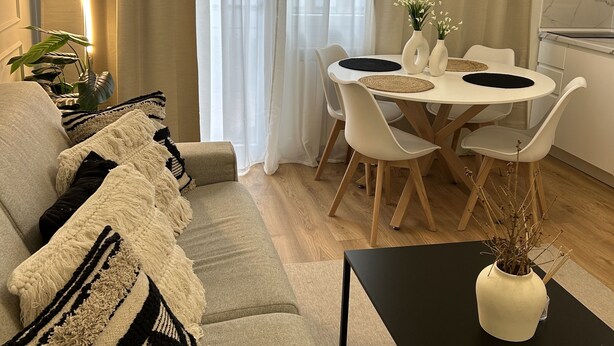En moderne stue med sofa, spisebord, stole og sofabord.
