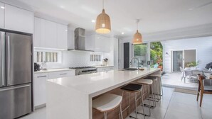 A modern kitchen with a central island, stainless steel appliances, and pendant lighting. - Casienda (Casuarina)